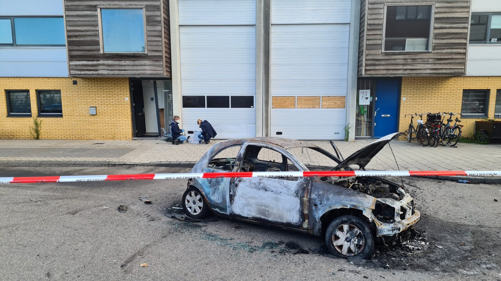 Een uitgebrande auto staat op de plek waar een ramkraak gepleegd is