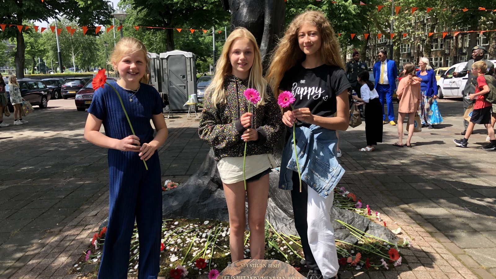 Kinderen met herdenkingsbloemem voor het monument 'De Levensboom'