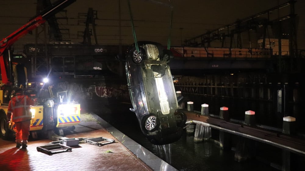Duikers halen man uit te water geraakte auto bij Oosterdokskade